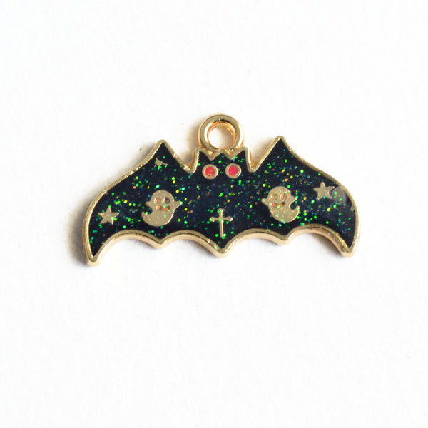 Black and green glittery bat charms decorated with two gold stars, two ghosts, a cross and two red eyes