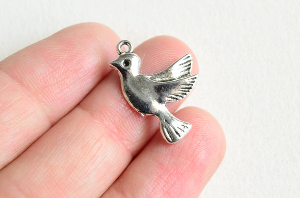 silver dove charms sitting on three fingers