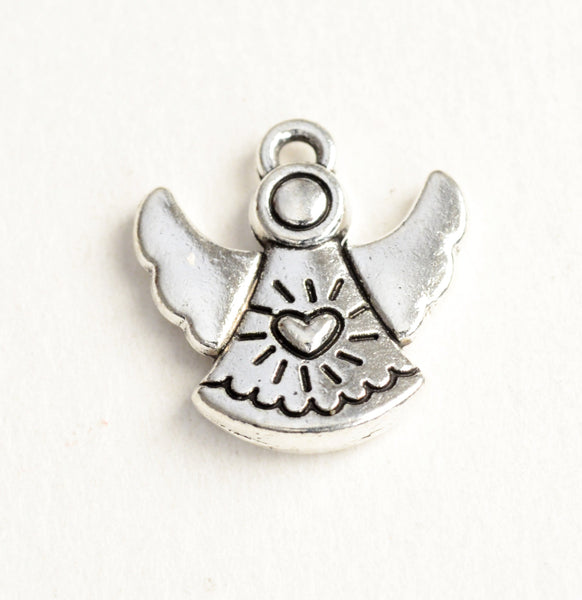 tiny silver angel charm with smooth wings and a heart with scallops on a fan shaped dress